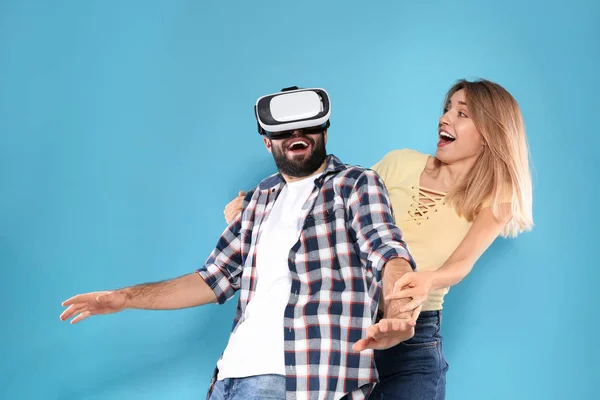 Jovem jogando videogames com fone de ouvido VR e mulher emocional no fundo de cor — Fotografia de Stock