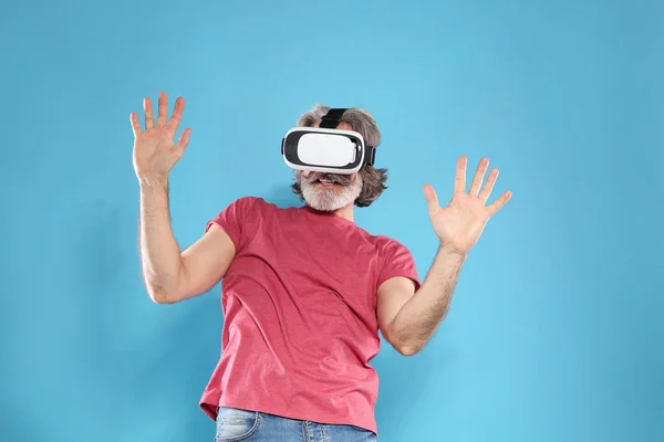 Homem maduro emocional jogando videogames com fone de ouvido de realidade virtual no fundo de cor — Fotografia de Stock