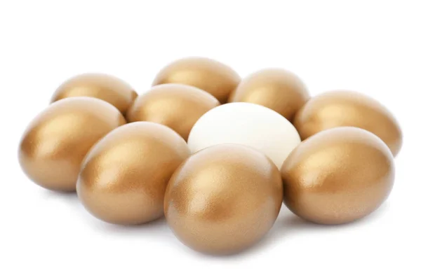 Gewone ei onder gouden degenen op witte achtergrond — Stockfoto
