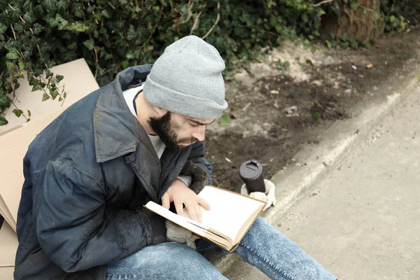 Homem pobre sem-teto com livro na rua na cidade — Fotografia de Stock