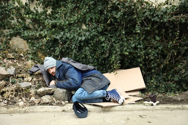 Pobre sem-teto deitado na rua na cidade — Fotografia de Stock