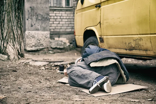 Poor homeless man lying near van outdoors — Stock Photo, Image