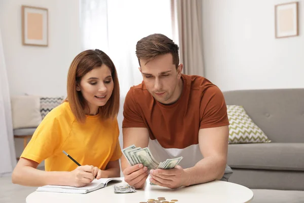 Pareja contando dinero en la mesa en la sala de estar —  Fotos de Stock