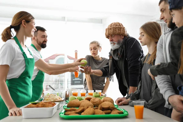 Pobres que reciben comida de voluntarios en el interior — Foto de Stock