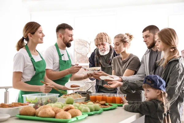 Voluntários dando comida para pessoas pobres dentro de casa — Fotografia de Stock