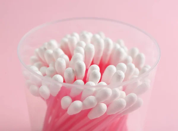 Plastic container with cotton swabs on color background, closeup