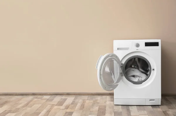 Máquina de lavar roupa moderna com lavanderia perto da parede de cor, espaço para texto — Fotografia de Stock