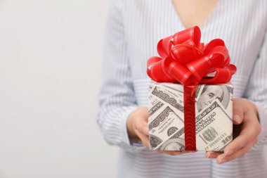 Kadın tutan hediye kutusu ışık arka planda dolar sarılmış, çekim
