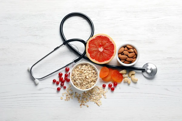 Produits sains pour le cœur et stéthoscope sur fond en bois, pose plate — Photo