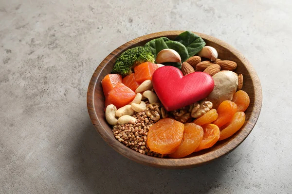 Bowl with heart-healthy products on grey background, space for text