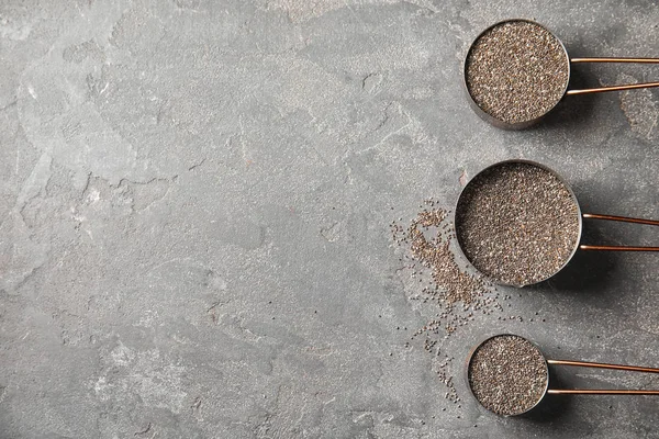 Cacerolas con semillas de chía sobre fondo gris, planas. Espacio para texto — Foto de Stock