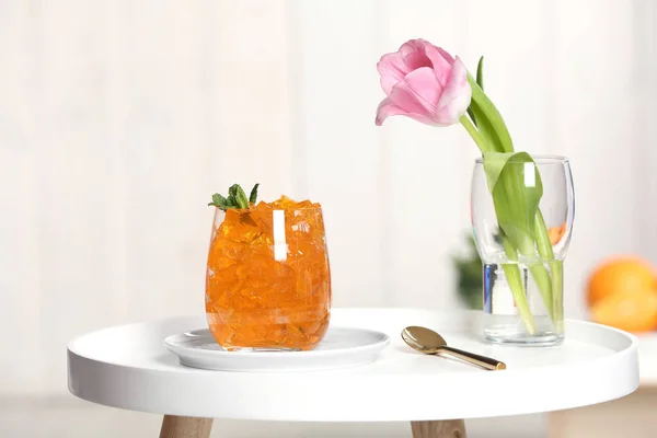 Bulanık arka plana karşı masada jöle ve çiçek bardağı — Stok fotoğraf