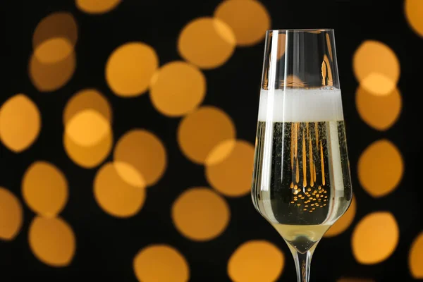 Glass of champagne against blurred lights. Space for text — Stock Photo, Image