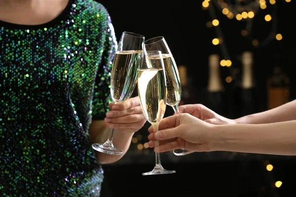 People clinking glasses of champagne on blurred background, closeup