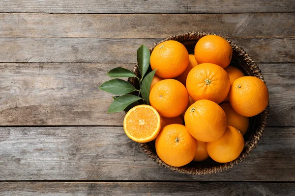 Miska s zralými pomeranči na dřevěném podkladu, pohled shora. Místo pro text — Stock fotografie