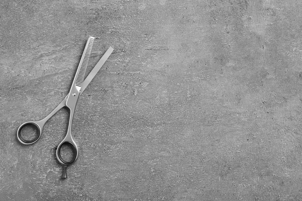 Thinning scissors and space for text on grey background, top view. Hairdresser tool