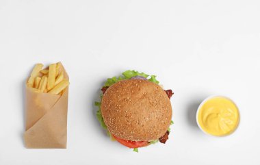 Beyaz arka planda lezzetli burger, patates kızartması ve sos, üst görünüm
