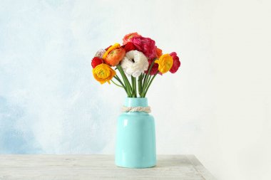 Renkli arka plana karşı masada güzel Ranunculus çiçekler ile vazo