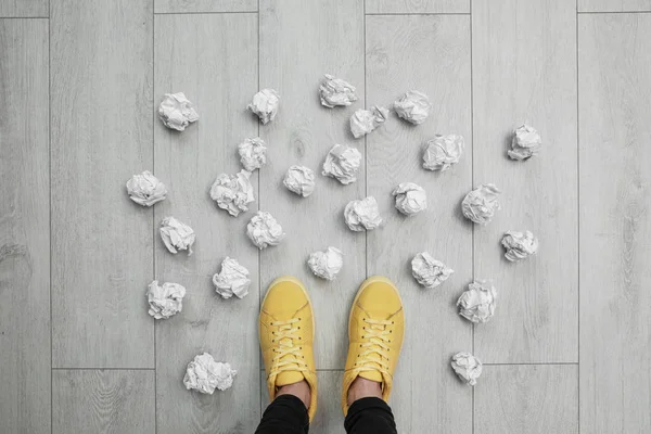 Closeup of person's feet surrounded by crumpled paper on floor, top view. Lack of ideas — Stock Photo, Image