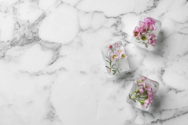 Квіткові кубики льоду на мармуровому тлі, вид зверху. Простір для тексту — стокове фото