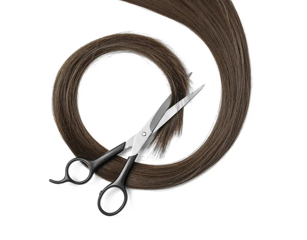 Cheveux bruns et ciseaux sur fond blanc, vue de dessus. Service de coiffure — Photo