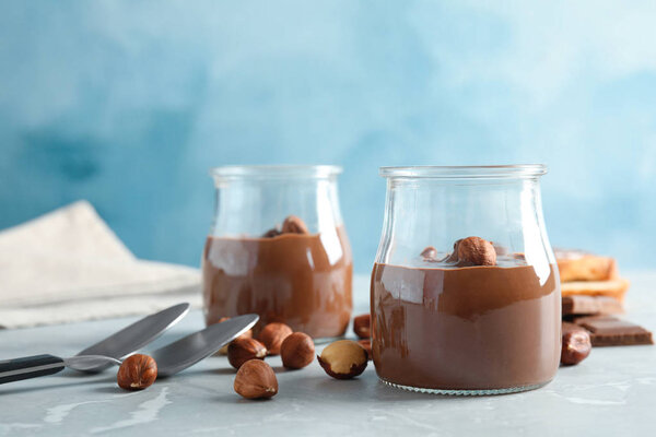 Glass jars with tasty chocolate cream served on table
