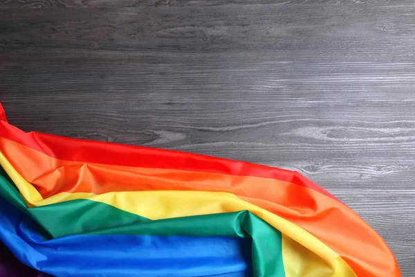 Bandera gay arco iris brillante sobre fondo de madera, vista superior con espacio para el texto. Comunidad LGBT —  Fotos de Stock