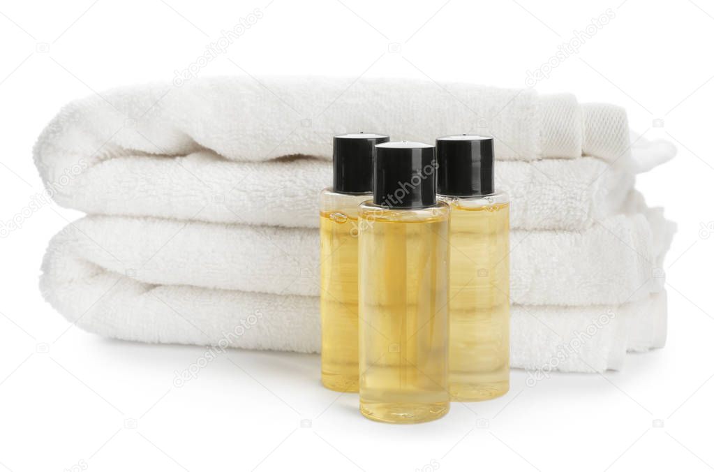 Mini bottles with cosmetic products and towels on white background. Hotel amenities