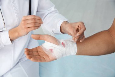 Kadın doktor Kliniği, closeup genç adamın elinde bandaj uygulayarak. İlk yardım