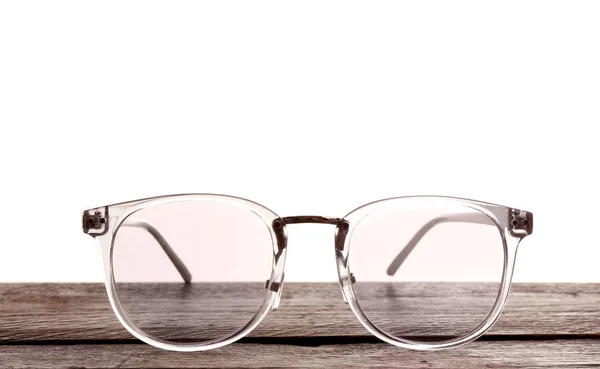 Okulary na drewnianym stole na białym tle. Konsultacje okulisty — Zdjęcie stockowe