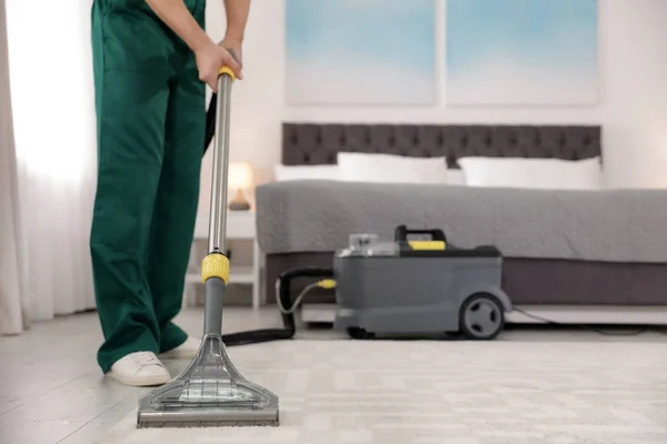 Petugas kebersihan profesional mengeluarkan kotoran dari karpet dengan vacuum cleaner di kamar tidur, closeup. Ruang untuk teks — Stok Foto