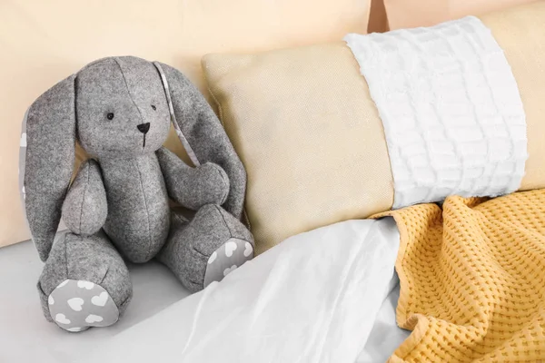 Lindo conejo de juguete en la cama en el interior de la habitación del niño. Espacio para texto —  Fotos de Stock