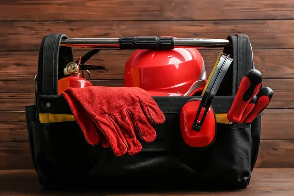 Bolso negro con herramientas de construcción sobre mesa sobre fondo de madera — Foto de Stock