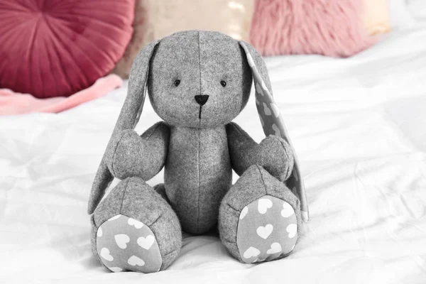 Cute stuffed toy rabbit on comfortable bed in child\'s room interior