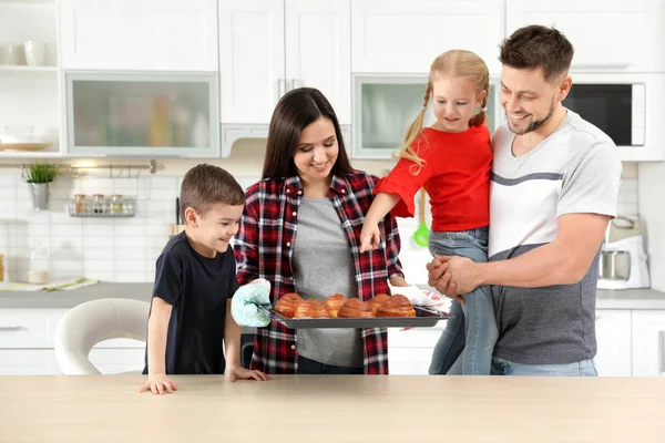 Famille heureuse avec plateau de petits pains cuits au four dans la cuisine — Photo