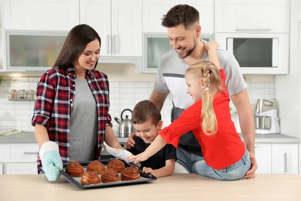 Lycklig familj med bricka med ugnsbakade bullar i köket — Stockfoto