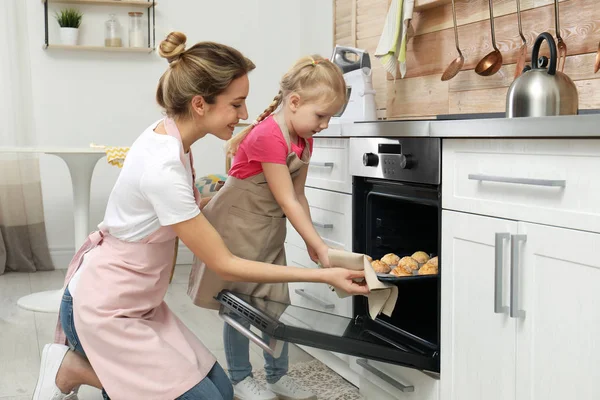 Ibu dan putrinya mengambil kue dari oven di dapur — Stok Foto