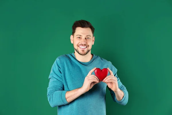 Muž, který držel dekorativní srdce na barvu pozadí — Stock fotografie