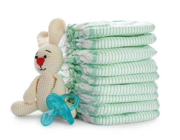 Pilha de fraldas descartáveis e acessórios para bebês no fundo branco — Fotografia de Stock