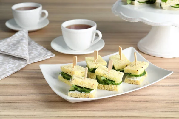 Plate with traditional English cucumber sandwiches on table