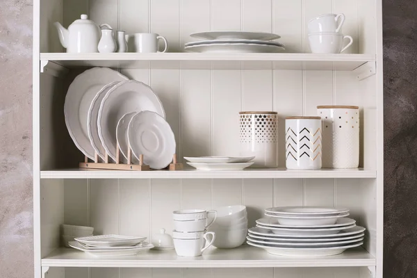 Elegante soporte de almacenamiento con diferentes vajilla de cerámica en casa —  Fotos de Stock