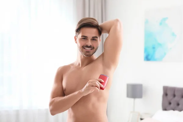 Csinos, fiatal férfi dezodor hálószobában alkalmazása — Stock Fotó