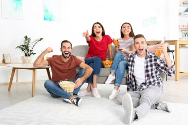Genç arkadaşlar oturma odasında televizyon izliyor. Spor kanalı
