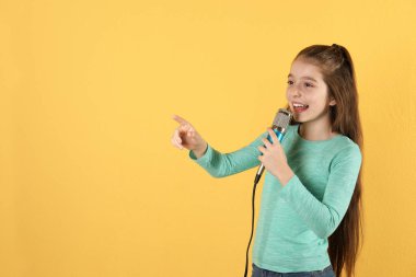 Sevimli kız renkli arka planda mikrofon şarkı. Metin için alan