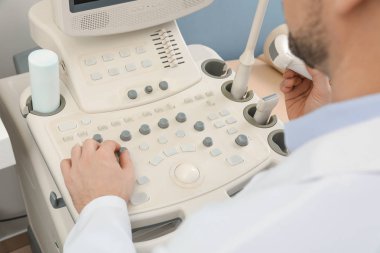Sonographer operating modern ultrasound machine in clinic, closeup clipart