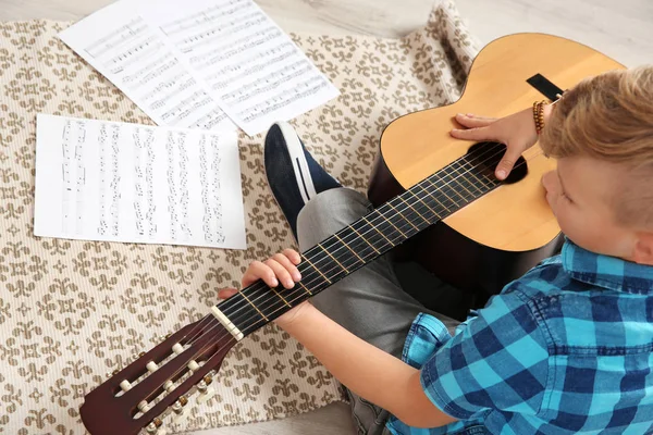 Niño tocando la guitarra en el suelo en la habitación — Foto de Stock