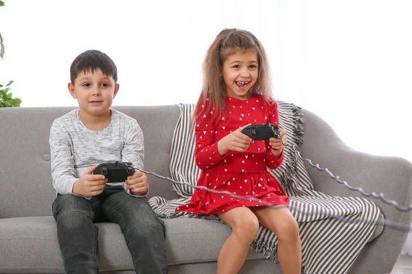 Leuke kinderen spelen video game op de Bank in de woonkamer — Stockfoto