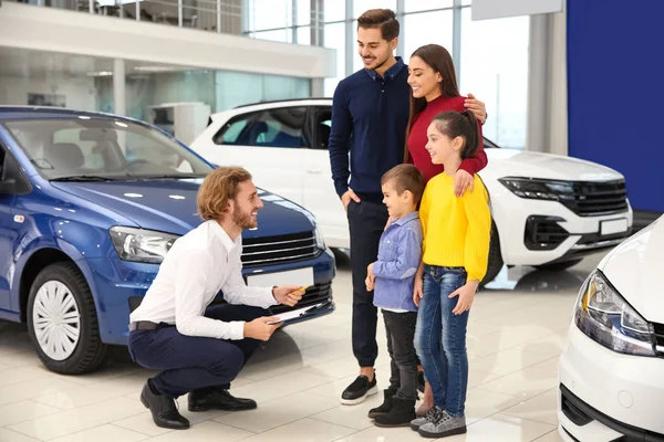 Vendedor de carros trabalhando com a família na concessionária — Fotografia de Stock