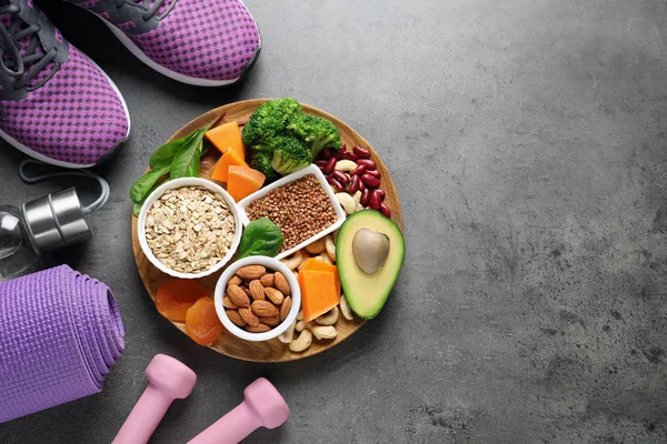 Plate with heart-healthy products and sports equipment on grey background, flat lay. Space for text