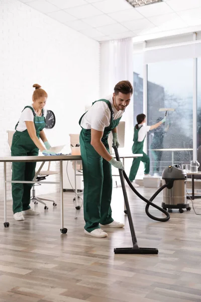 Equipo de conserjes profesionales trabajando en una oficina moderna. Servicio de limpieza — Foto de Stock